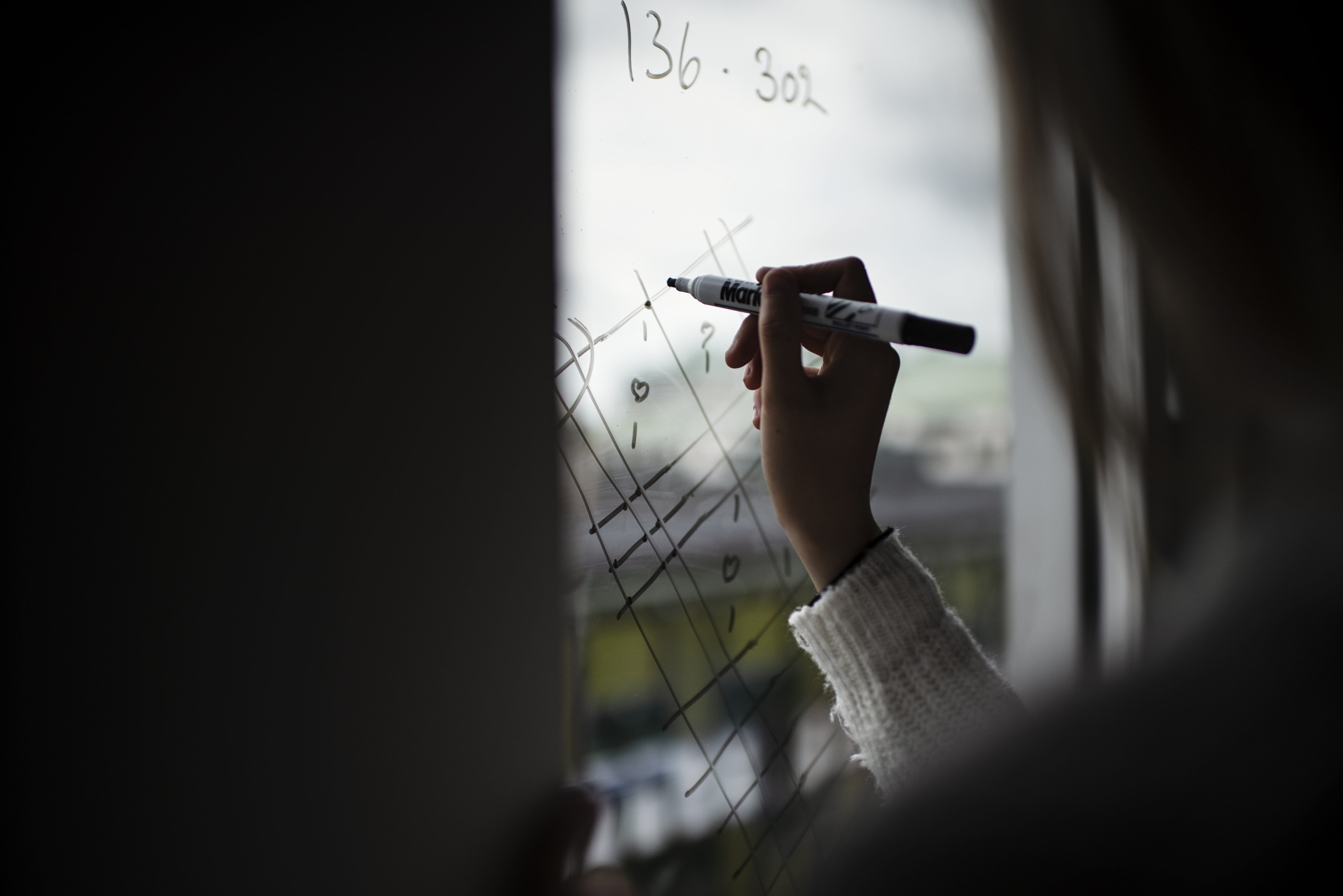 En person skriver formler på en whiteboard.