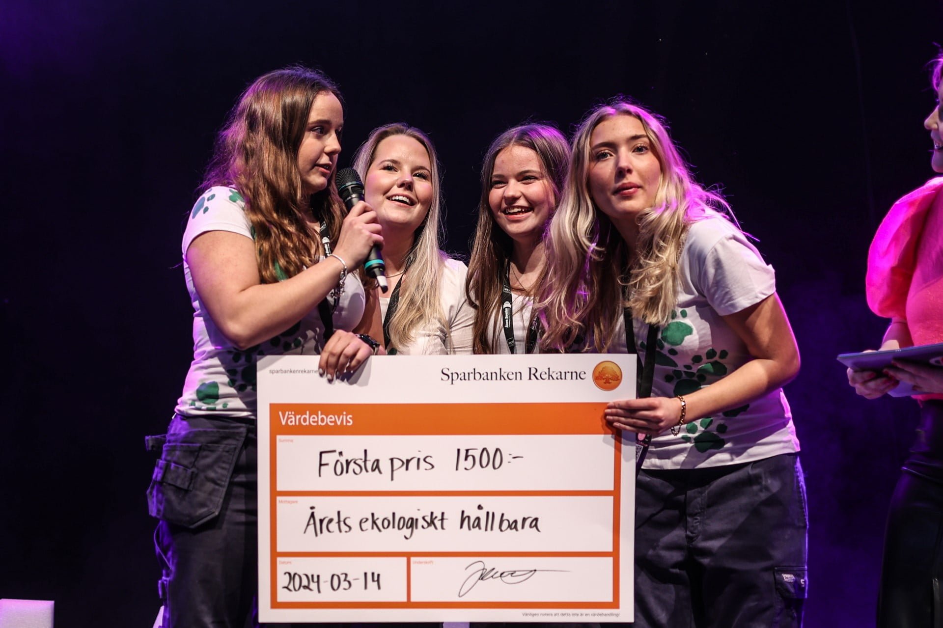 Fyra elever håller en stor prischeck på scen.