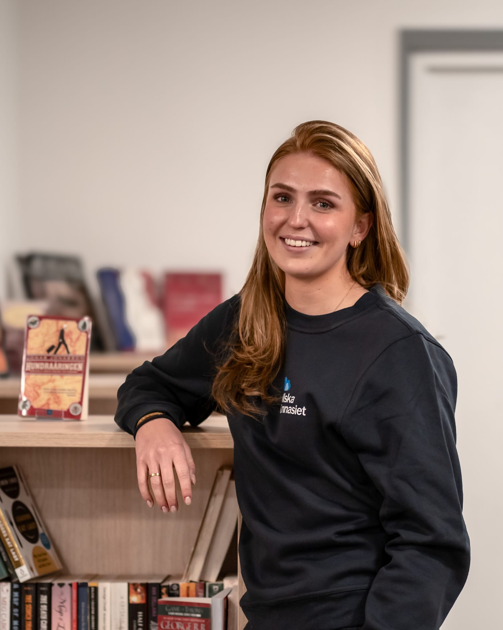 Glad tjej i skolbibliotek. Träffa henne på öppet hus.