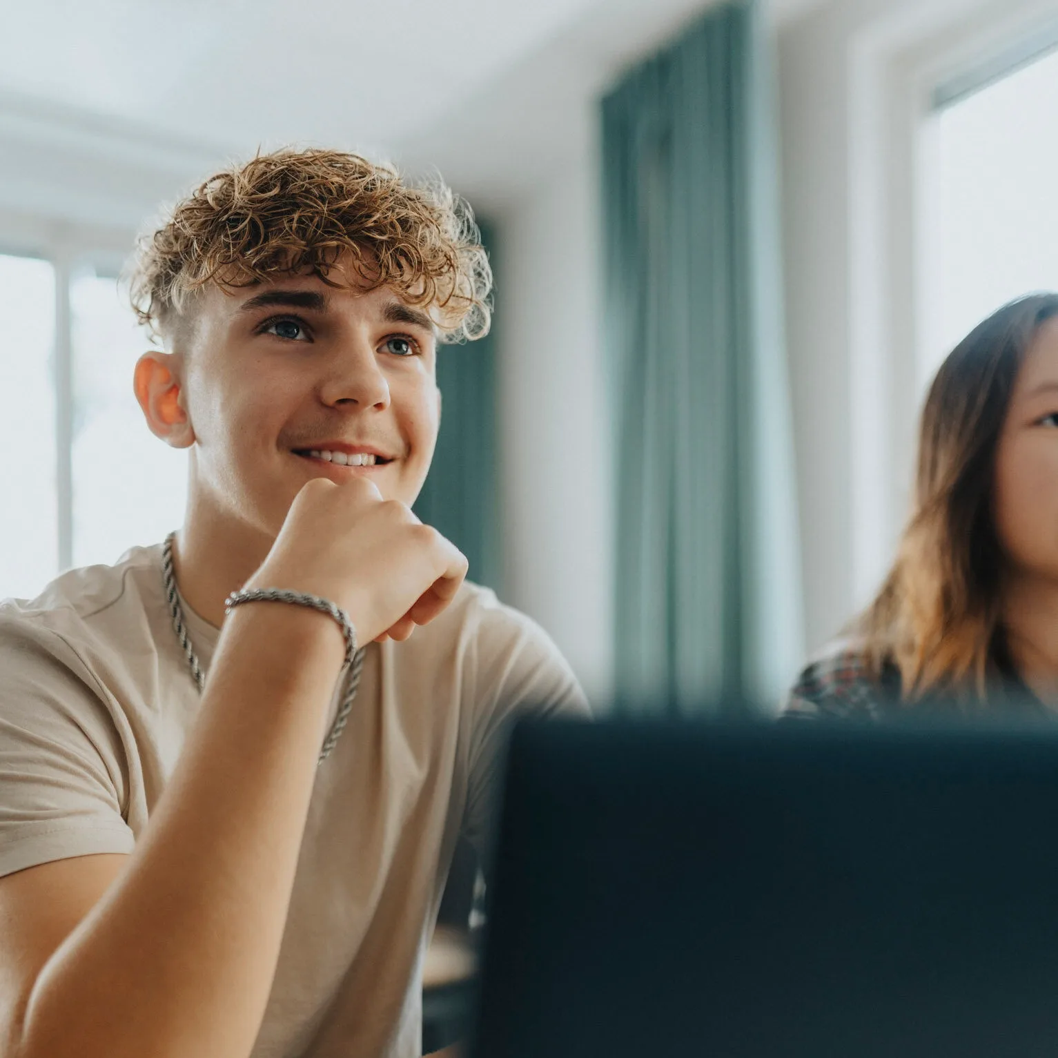 Kille med lockigt hår sitter framför laptop i klassrum
