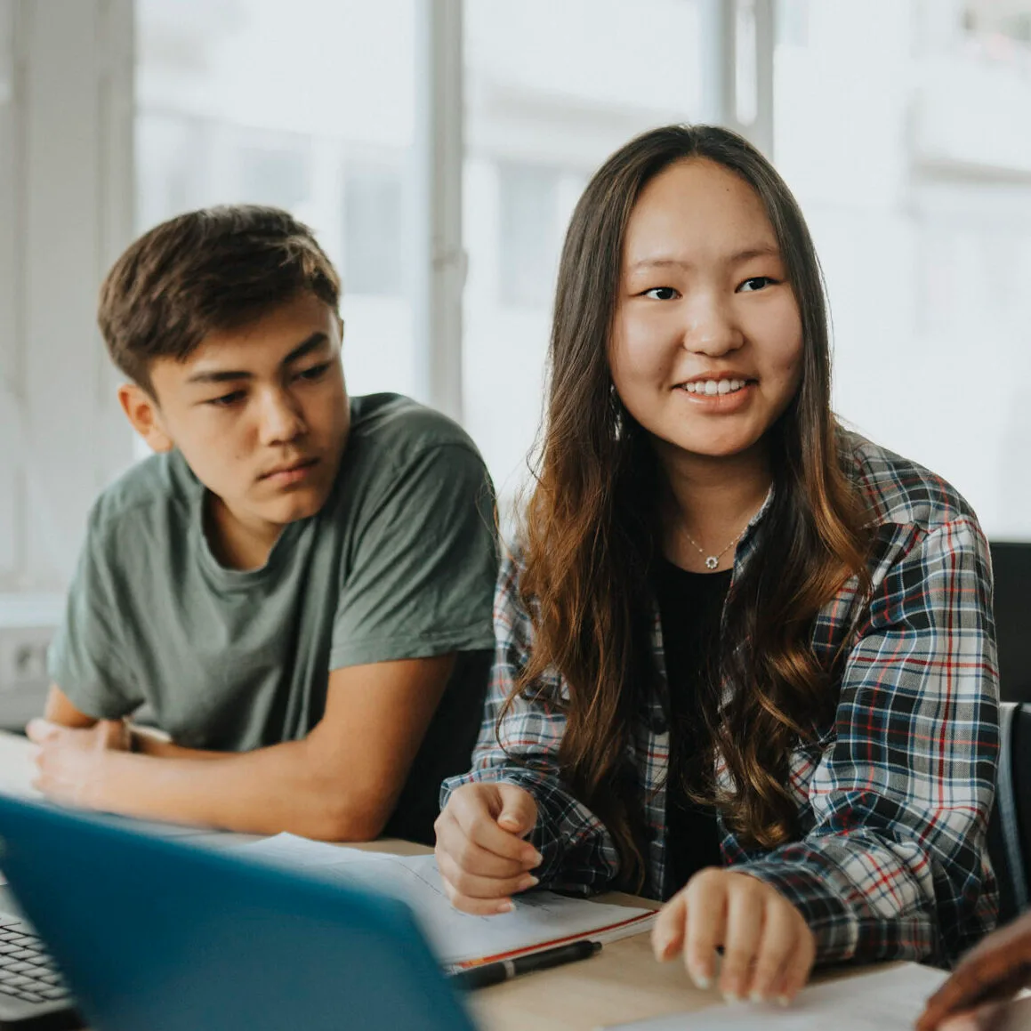 En ung tjej och kille vid ett bord i klassrum