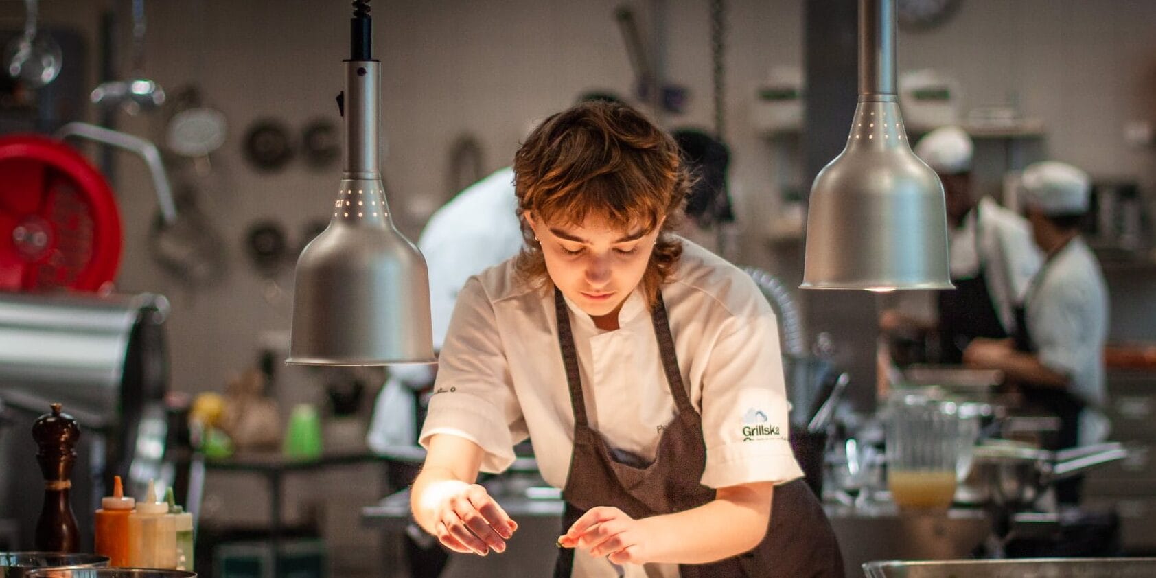 Elev på restaurangprogrammet som står i kockkläder och lägger upp mat