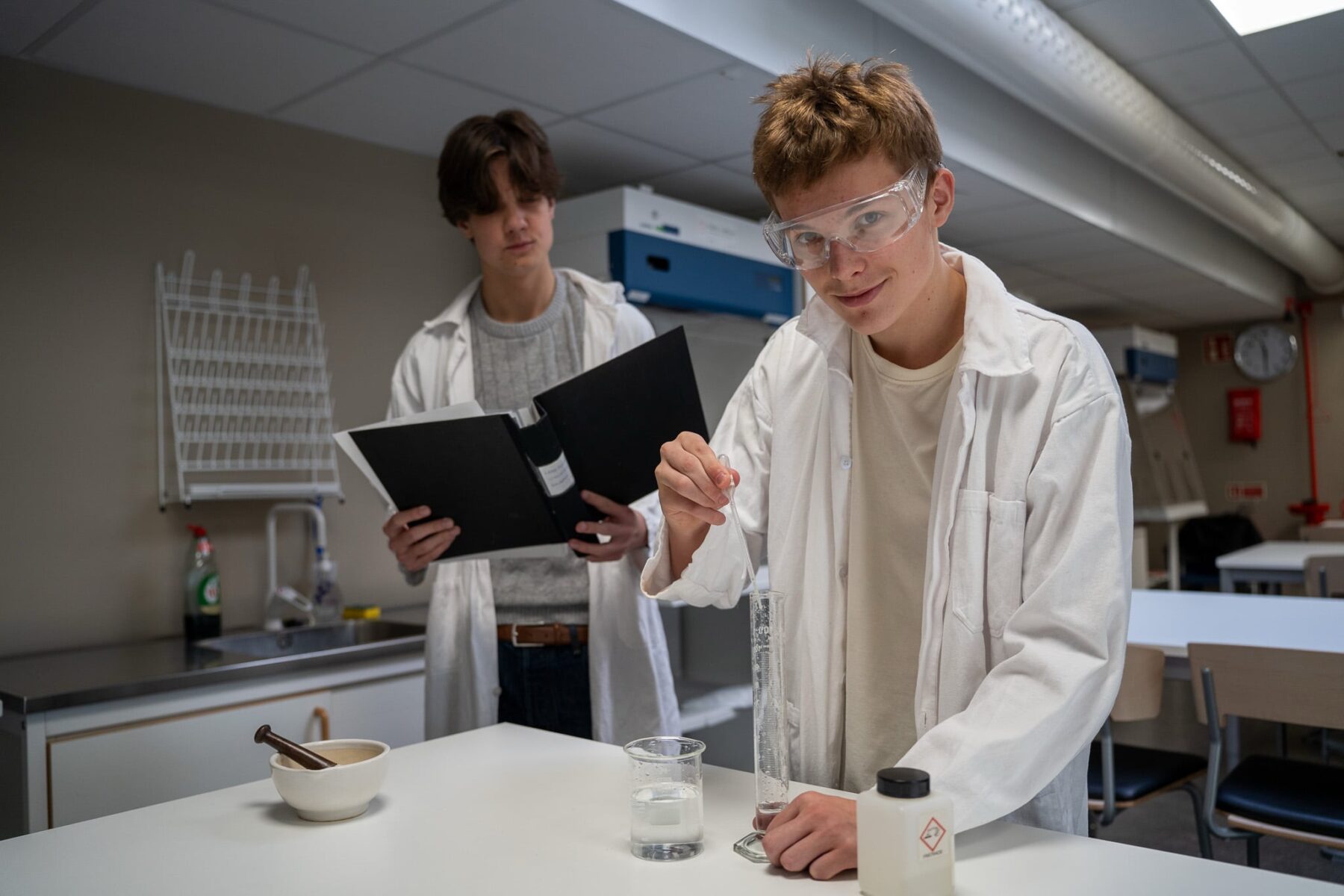 Två killar som pluggar på gymnasiet och står i ett laboratorium