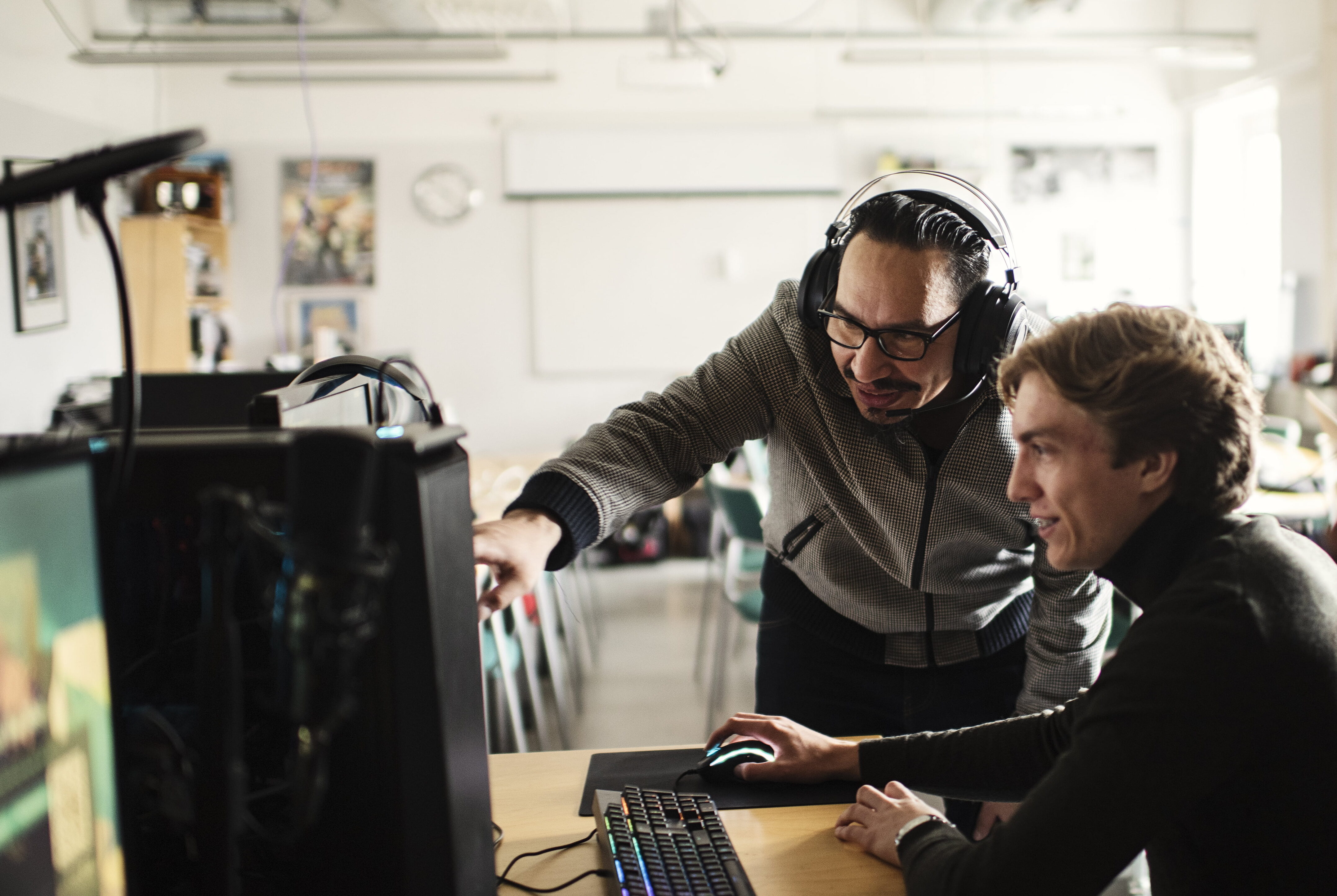 Elev på El- och energi&shy;programmet IT får handledning vid en dator i ett klassrum.