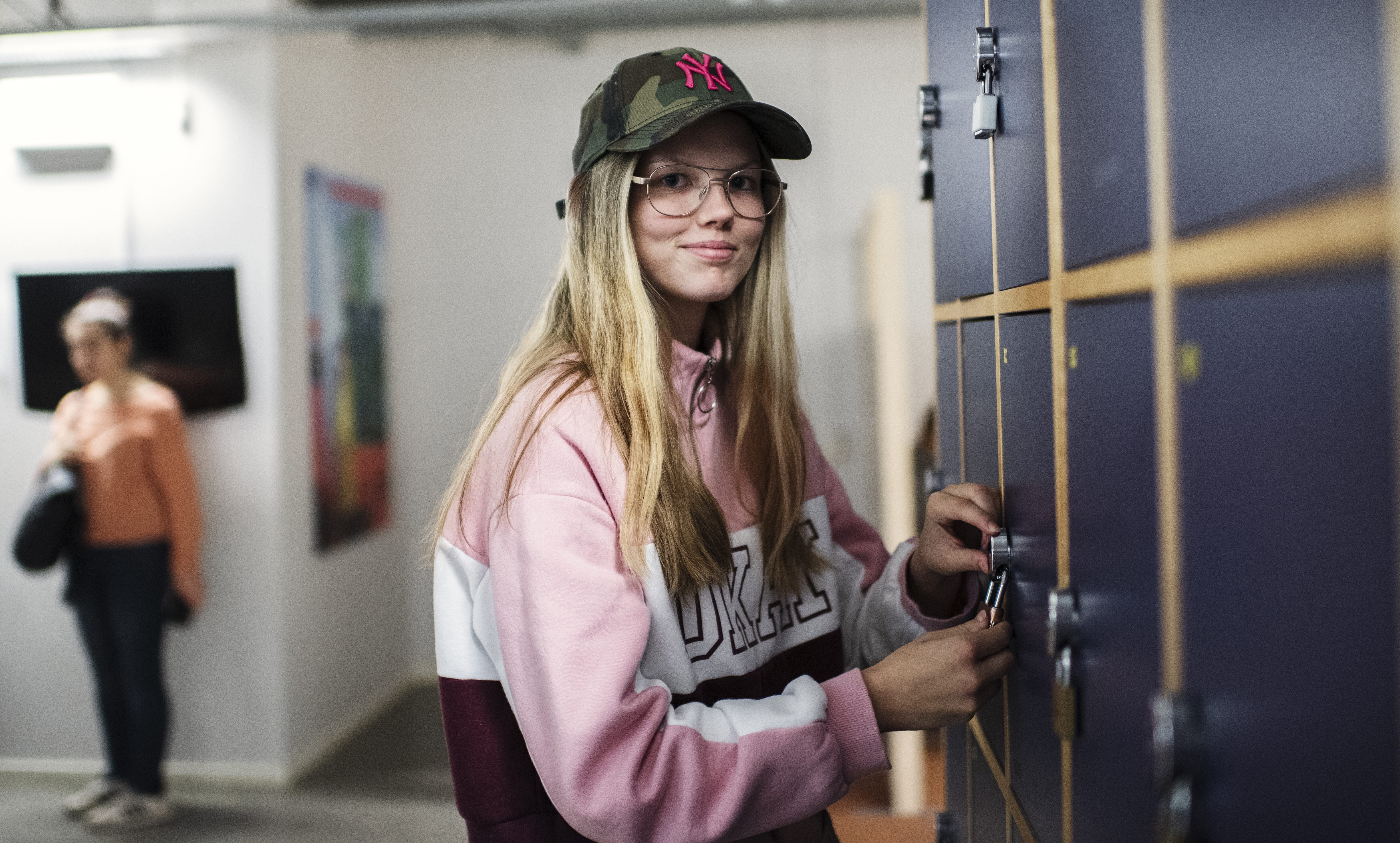 Elev på Anpassad gymnasieskola Administration, handel och varuhantering låser upp ett skåp i en skolkorridor.