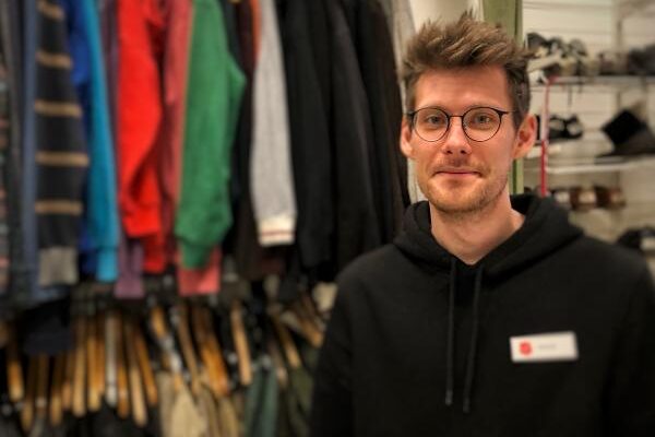 Porträtt av eleven Mattias framför en klädstång, studerar till socialpedagog.